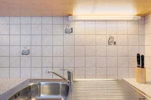 a stainless steel sink in a kitchen with white tiles at Mair am Tinkhof in Selva dei Molini +55 photos