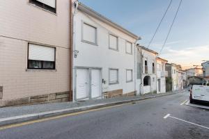 a white building with white doors on a street at Tour House in Rio Tinto