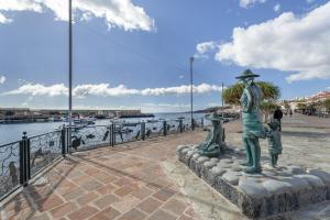 a statue of a man and two children near the water at Apartamento Estrella in Candelaria