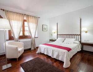 a white bedroom with a bed and a chair at Gran Castanyer in Viladrau
