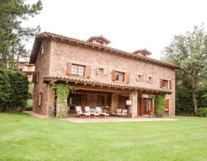 a large brick house with chairs and tables on a lawn at Gran Castanyer in Viladrau