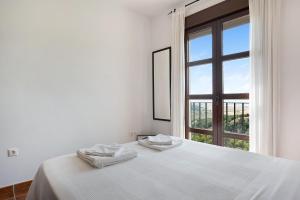 a white bedroom with a bed and a window at Cobijadas75 Corredera in Vejer de la Frontera