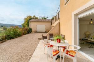 a patio with a table and chairs and a building at Gîte du Badassier in Blauvac