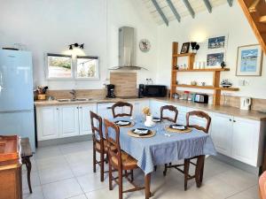 a kitchen with a table and chairs and a kitchen with white cabinets at Maison De Plage La Payade in Pirou