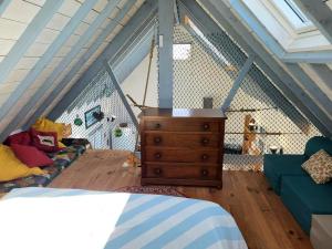a room with a bed and a dresser in a attic at Maison De Plage La Payade in Pirou