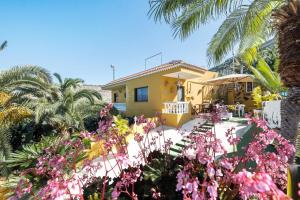 a yellow house with palm trees and pink flowers at Finca Alejandrina in La Guancha