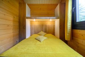 a small bedroom with a yellow bed in a cabin at Chalet Spa 2 Terrasse des Bouleaux in Ranspach +17 photos