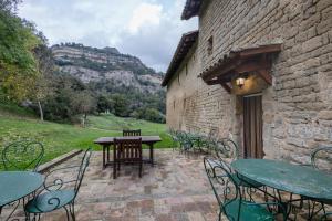 a patio with tables and chairs and a stone building at Mas Vinyoles in Centellas