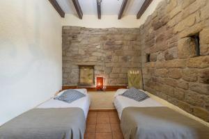 two beds in a room with a stone wall at Mas Vinyoles in Centellas +33 photos