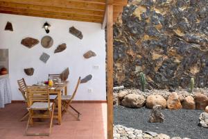 a dining room with a table and a rock wall at Casa Valista in Tijarafe