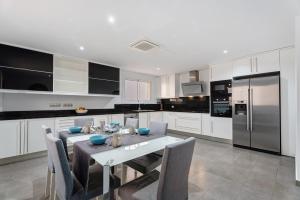 a white kitchen with a table and a refrigerator at Villa Aurora Playa La Arena in Puerto de Santiago