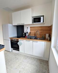 a white kitchen with a sink and a microwave at Appartement lumineux et spacieux 70m2 proche de tout - 3 chambres in Nantes