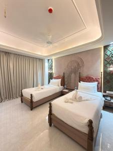 a hotel room with two beds with white sheets at Vetiver Grand in Jabalpur