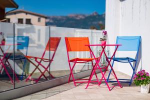 three colorful chairs and a table on a balcony at EnSe Affittacamere in Tortolì