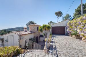 a house with a garage and a palm tree in the driveway at Roc Blau in Begur