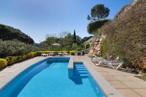 a swimming pool with two chairs and a table at Roc Blau in Begur