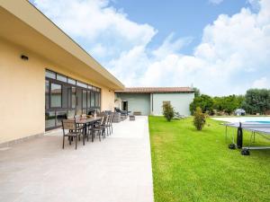 a patio with a table and chairs and a lawn at Villa Germano con piscina in Solarino