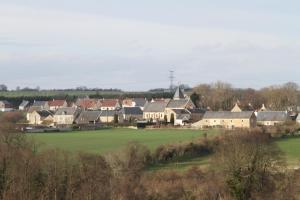 a village with houses and a green field at La Morinière in Vieux +5 photos