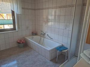 a bath tub in a tiled bathroom with a stool at Zweiraum-Ferienwohnung Mitte in Marienberg +2 photos