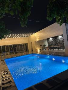 a large blue swimming pool in front of a building at night at Yerevan Street hotel in Yerevan