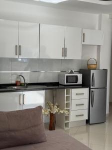 a kitchen with white cabinets and a stainless steel refrigerator at Urban Praia Maria - ApartHotel in Praia