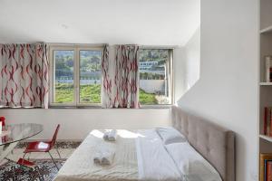 a bedroom with a bed and a table and two windows at Le Suite del Castello in Castellammare di Stabia