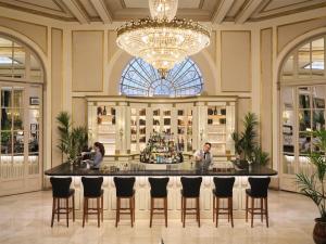 a bar in a hotel lobby with a chandelier at Hotel El Palace Barcelona in Barcelona