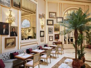 a restaurant with tables and chairs and portraits on the wall at Hotel El Palace Barcelona in Barcelona