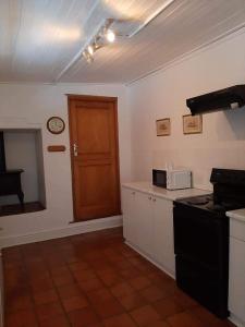 a kitchen with a stove and a clock on the wall at De Kothuize 18 in Graaff-Reinet