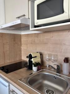 a kitchen counter with a sink and a microwave at La nuit Douce in Annemasse
