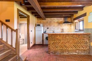 a kitchen with a brick counter and a refrigerator at Casa Alba in Bárcena de Cicero