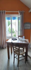 a table and a chair in a room with a window at Les Chambres De Martine Et Guy - in Sermaise