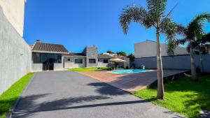a house with a palm tree and a swimming pool at Casa Beverly, com Piscina, 3 Quartos e Churrasqueira in Foz do Iguaçu
