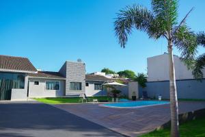 a palm tree next to a house with a swimming pool at Casa Beverly, com Piscina, 3 Quartos e Churrasqueira in Foz do Iguaçu