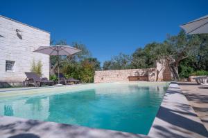 a swimming pool with an umbrella and chairs at Villa Trullo Vecchia Aia in Alberobello
