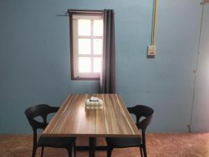 a wooden table with two chairs and a window at Happy house in Ban Khlong Son