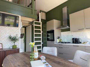 a kitchen with a table and a loft bed at De Ree Tiny House Tussen de Dijken in Driewegen