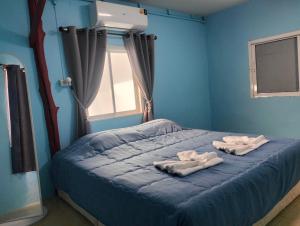 a blue bedroom with two towels on a bed at Happy house in Ban Khlong Son