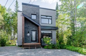 a modern house with a black brick facade at Le Taiga - Pool Table Nature Pet Friendly in Pont-Rouge