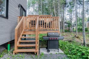a deck with a grill next to a house at Le Taiga - Pool Table Nature Pet Friendly in Pont-Rouge