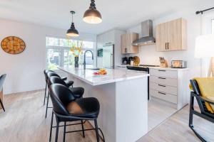 a kitchen with a white counter and black chairs at Le Taiga - Pool Table Nature Pet Friendly in Pont-Rouge +44 photos