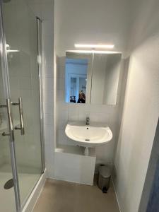 a white bathroom with a sink and a shower at Bleu Mandarou in Millau