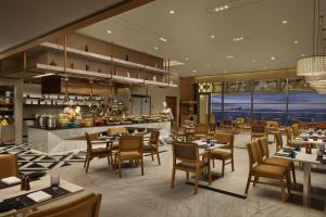 a restaurant with tables and chairs and a kitchen at Hyatt Place Bhopal in Bhopal