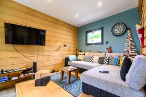 a living room with a couch and a flat screen tv at Le Chalet Milien in La Bresse