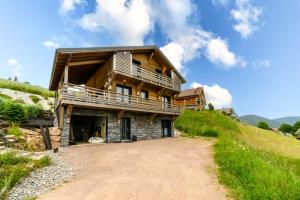 a large wooden house on a hill with a dirt road at Le Chalet Milien in La Bresse