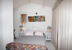 a white bedroom with a bed and two lamps at Duplex in Grosseto-Prugna