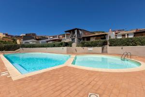 a large swimming pool in a yard with a brick patio at Casa Nuages in Badesi