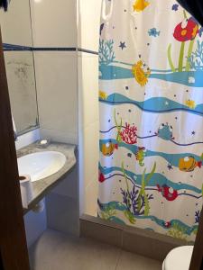 a bathroom with a shower curtain with a sink at Refúgio da Vila in Ilhabela +4 photos