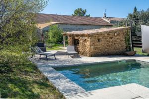 a swimming pool with two chairs and a stone building at Rose Antique in Valréas