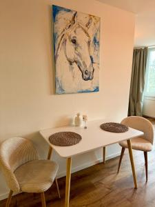 a table with two chairs and a painting of a horse at Aarebar Rooms in Solothurn